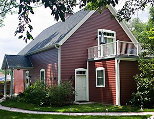 Red building with green grass, windows, and doors with white trim.