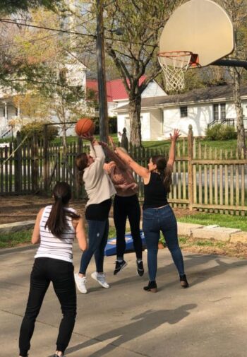 People playing basketball in the back yard.